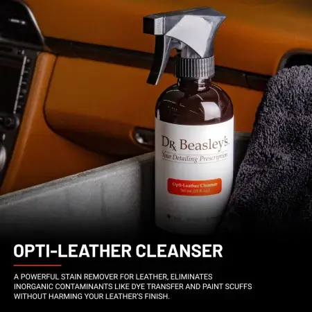 A 12 fl oz bottle of Opto\i-Leather Cleanser positioned inside a car with brown leather interior.