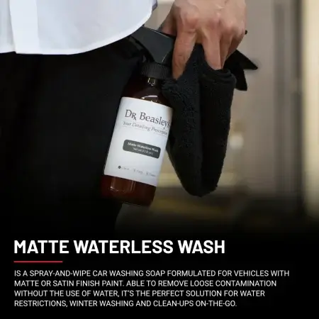 A man wearing a white shirt and black trousers holds a 12 fl oz bottle of Matte Waterless Wash.