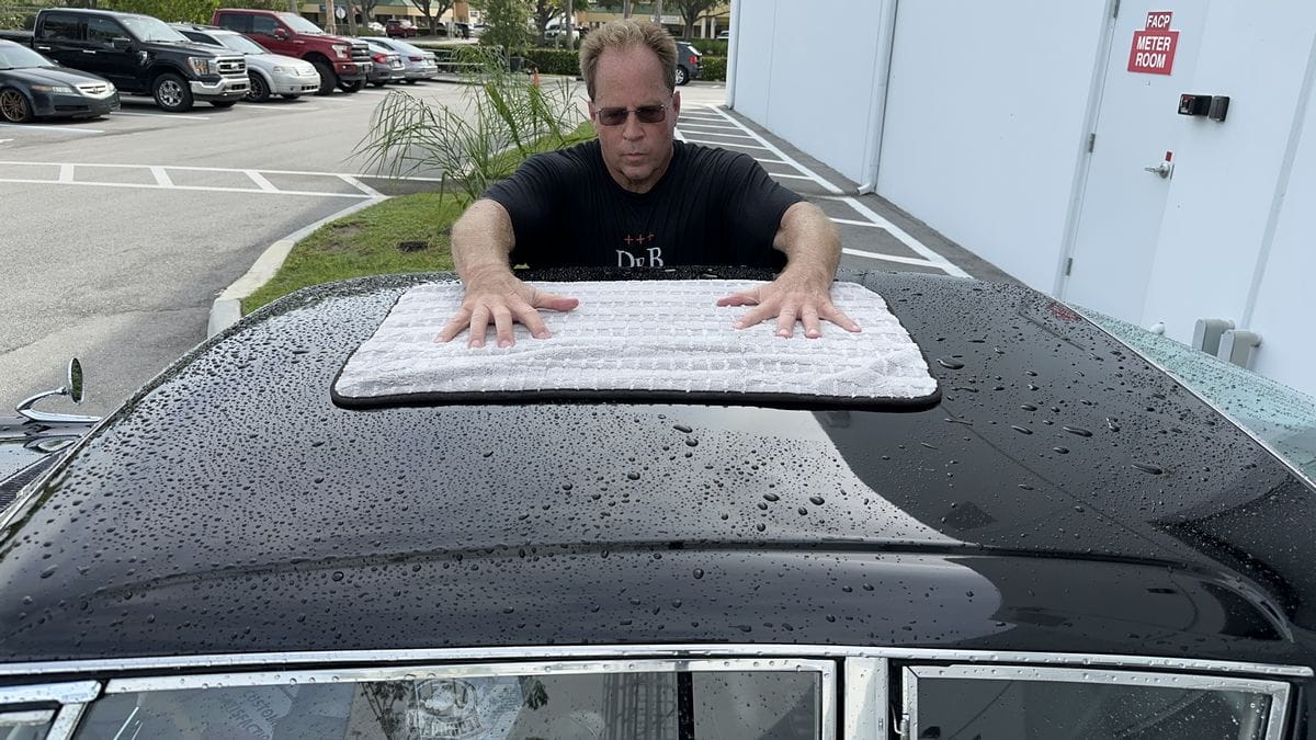 Drying a black car with a microfiber towel