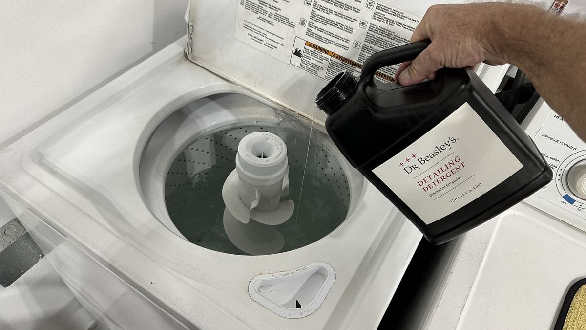 Pouring detergent in washing machine to clean microfiber towels