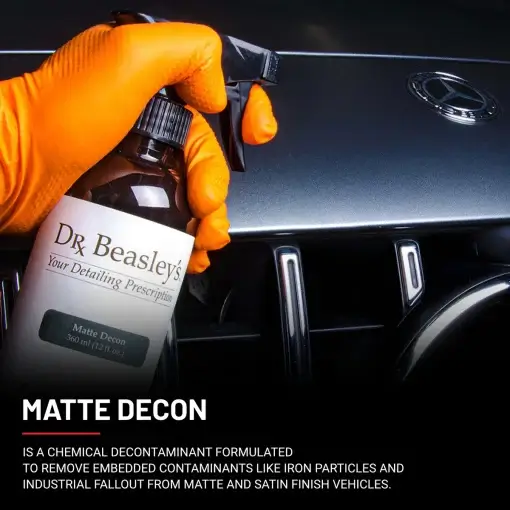 A hand wearing an orange glove holds a Matte Decon bottle in front of a matte grey Mercedes