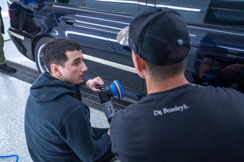 Instructor and Student discussing the paint correction of an E39 M5 that is being worked on.