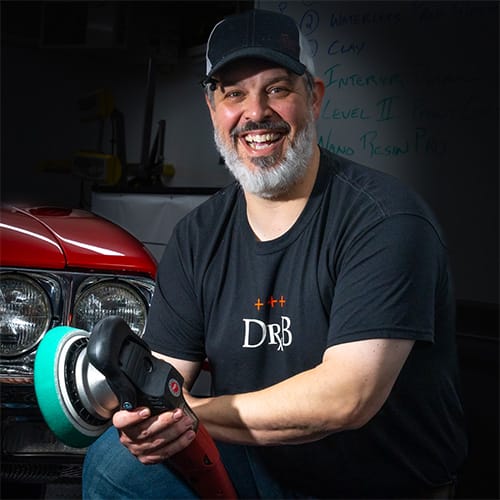 Director of Success at Dr. Beasley's Chris Racana smiling in front of car.