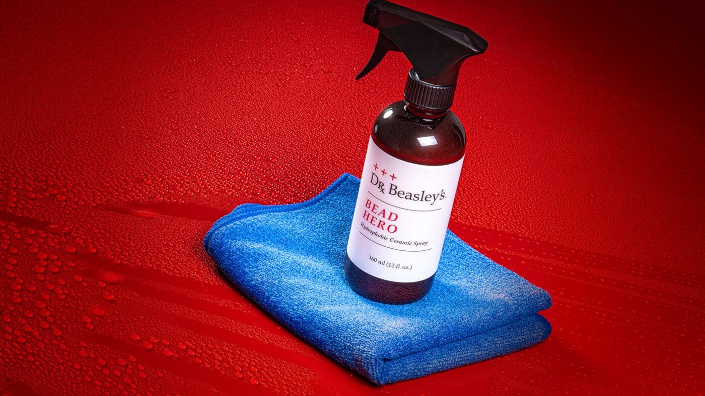 Dr. Beasley's Bead Hero on a blue microfiber towel resting on a car hood filled with beads of water.