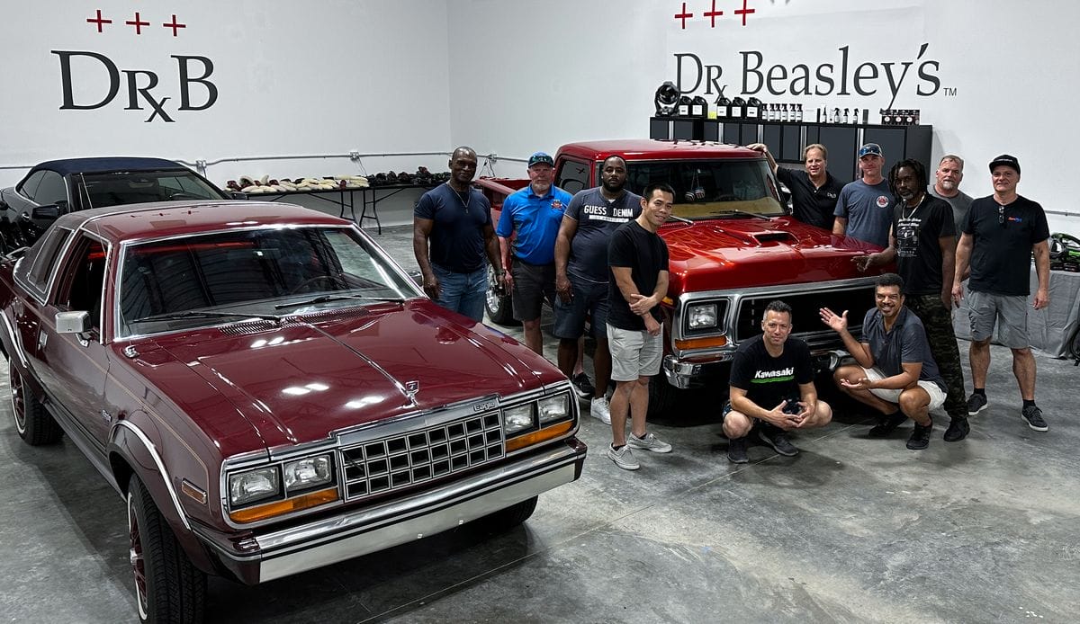 Students posing in front of cars after detailing