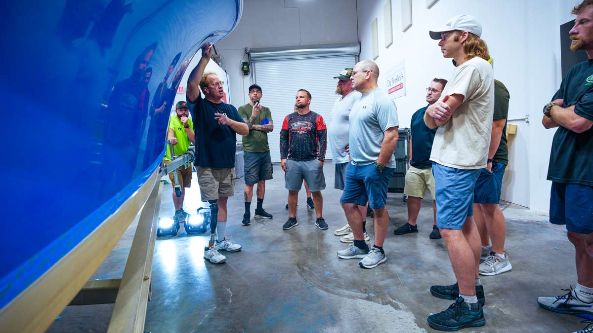 Mike Phillips speaks with marine detailing class students around boat