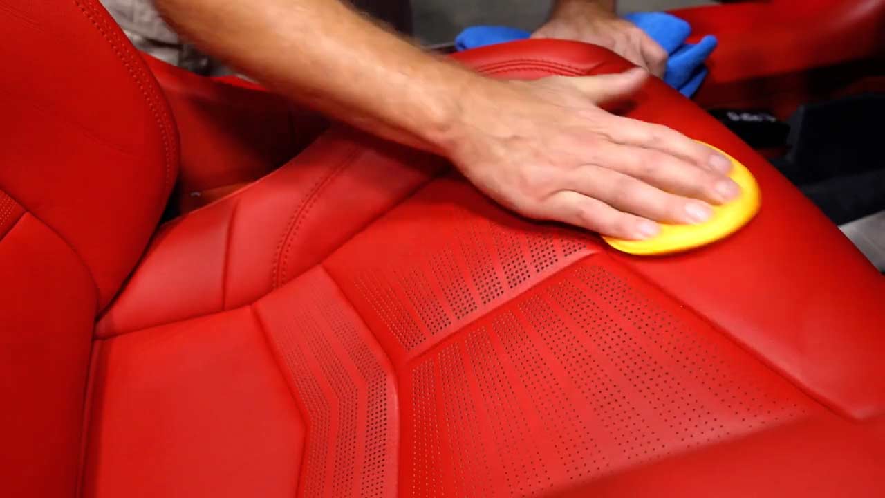Applying leather conditioner to red Corvette leather seats
