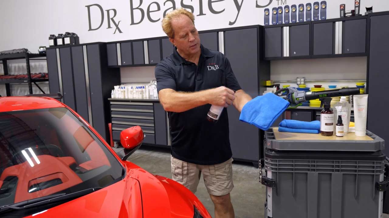 Spraying Dr. Beasley's Bead Hero into a microfiber towel before applying to Corvette