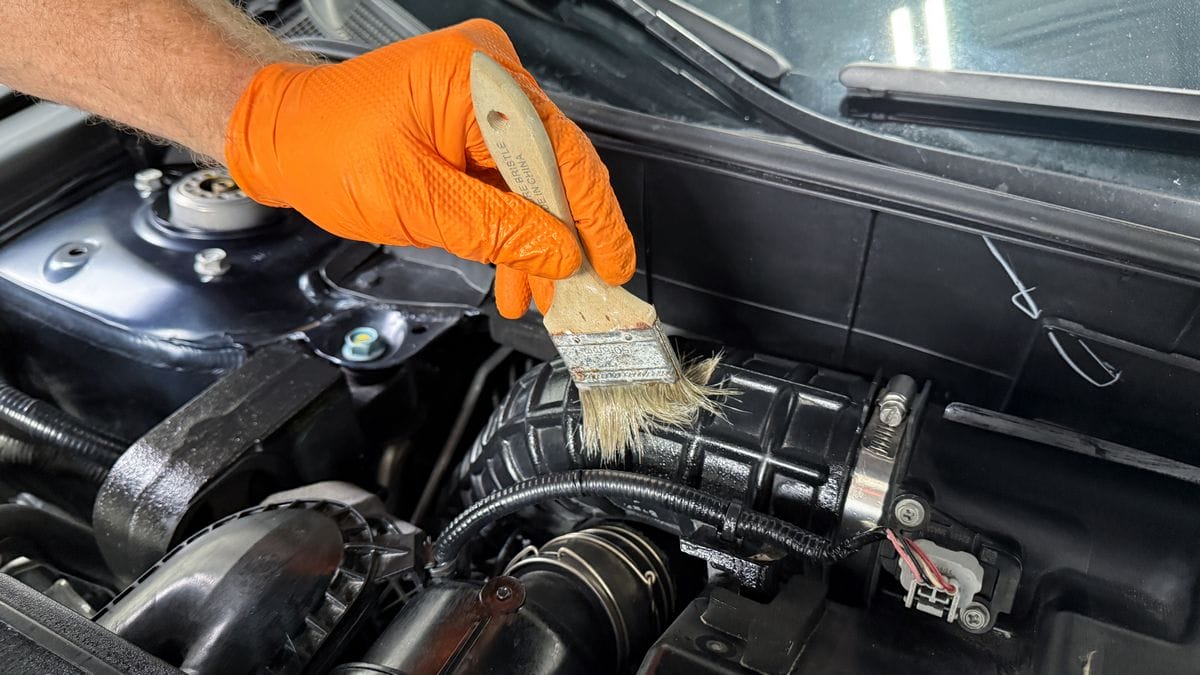 Applying plastic sealant to engine bay