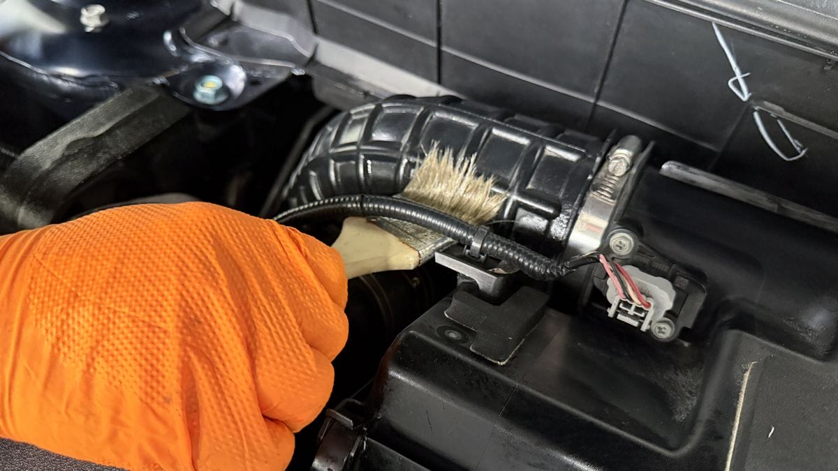 Applying plastic sealant to engine bay