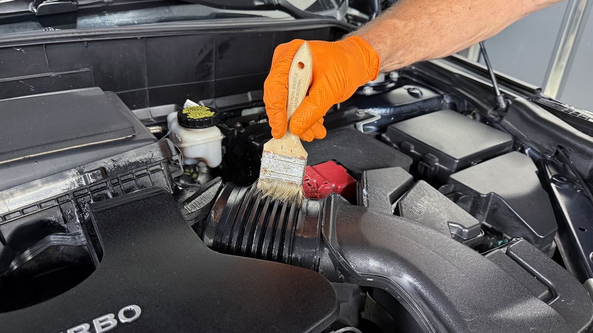 Applying plastic sealant to engine bay