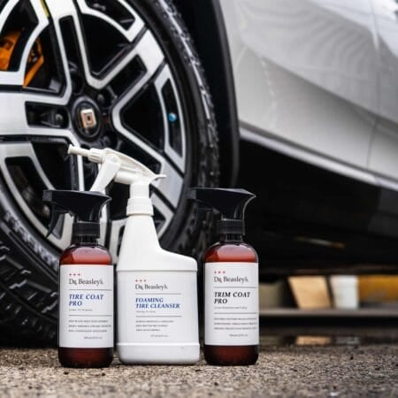 Dr. Beasley's Foaming Tire Cleanser, Trim Coat Pro and Tire Coat Pro after use in front of a white Rivian R1S
