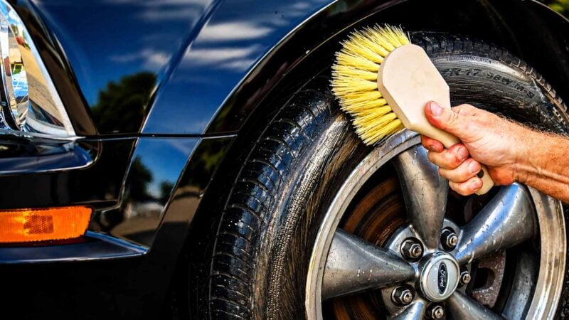 Step-by-step tire deep cleaning process showing a hand applying tire cleaner to a glossy black tire, with before-and-after contrast highlighting restored shine and protective coating.