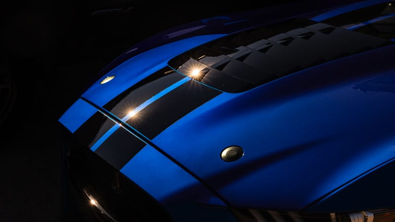 Blue sports car hood with black racing stripes