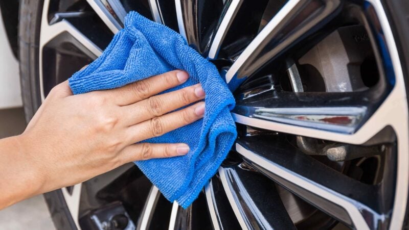 Microfiber towel wiping a car wheel during waterless wheel cleaning