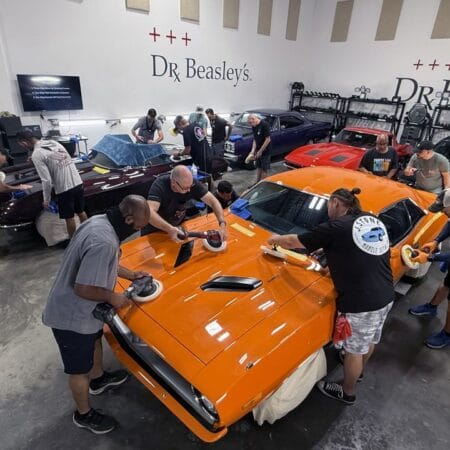 Students machine polishing an orange Plymouth Cuda and a burgundy Corvette during Mike Phillips’ detailing class in Stuart, Florida.
