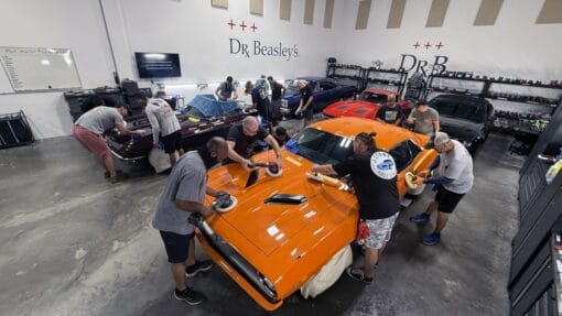Students machine polishing an orange Plymouth Cuda and a burgundy Corvette during Mike Phillips’ detailing class in Stuart, Florida.