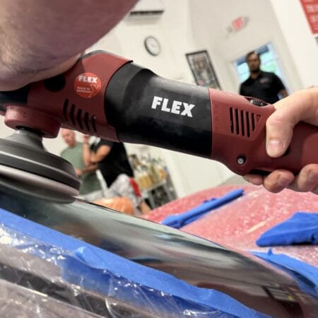 Close-up of a FLEX machine polisher working on a masked windshield during glass polishing practice.