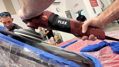 Close-up of a FLEX machine polisher working on a masked windshield during glass polishing practice.